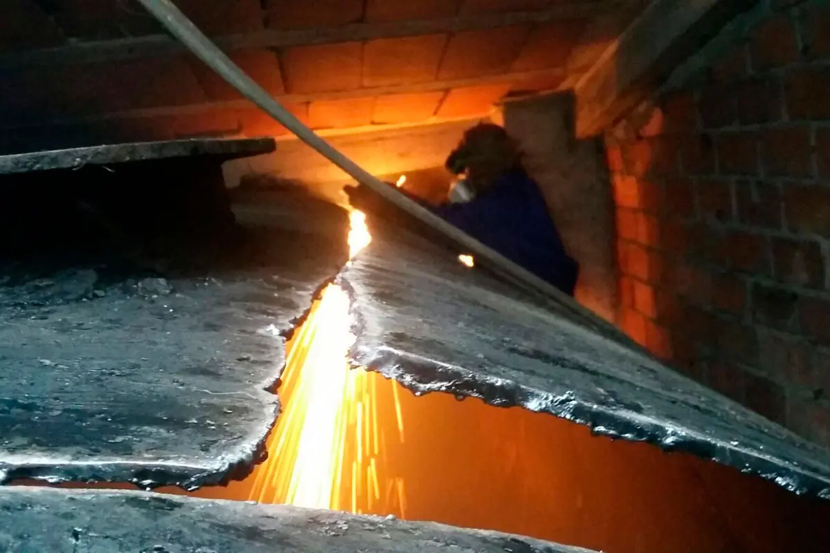Operario cortando un depósito metálico para su retirada